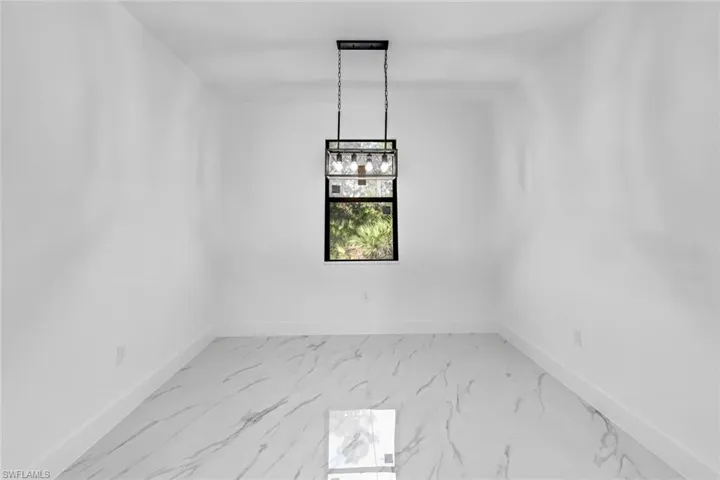 Unfurnished dining area featuring baseboards and light marble finish flooring