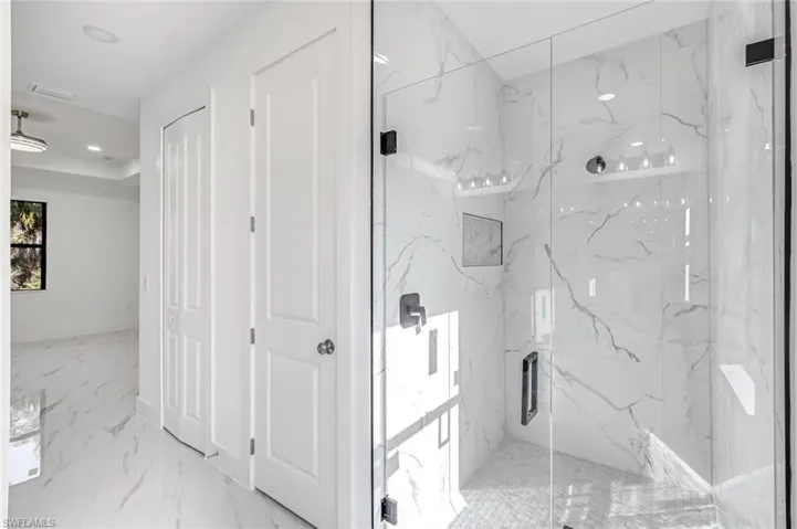 Bathroom featuring a marble finish shower, light marble finish floors, recessed lighting, and a closet
