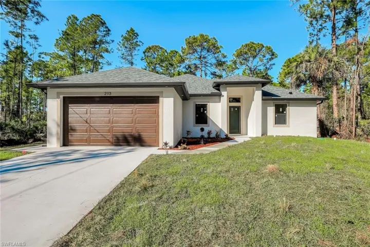 View of front of property featuring a front yard, stucco siding, driveway, a garage, and a shingled roof
