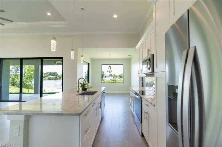 kitchen island with sink, a healthy amount of sunlight, sink, and stainless steel appliances