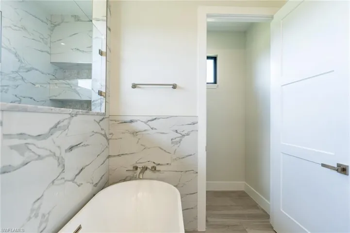 Bathroom with tile walls, hardwood / wood-style floors, and separate shower and tub