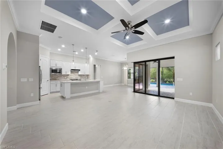 Unfurnished living room with coffered ceiling, recessed lighting, a ceiling fan, arched walkways, and crown molding