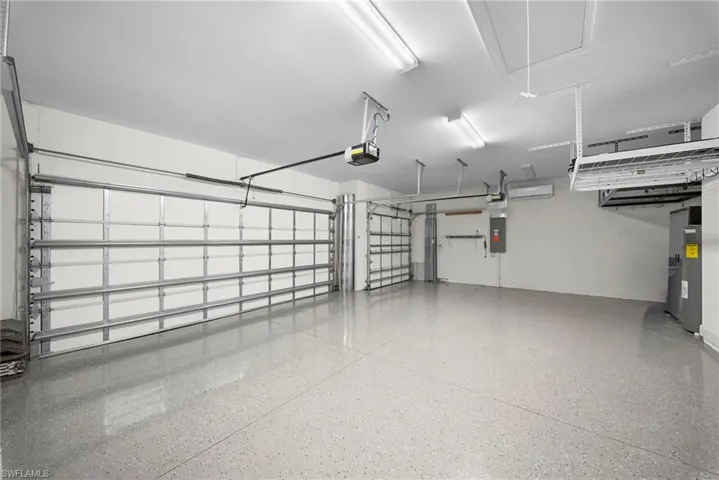 Garage featuring water heater, electric panel, and a garage door opener