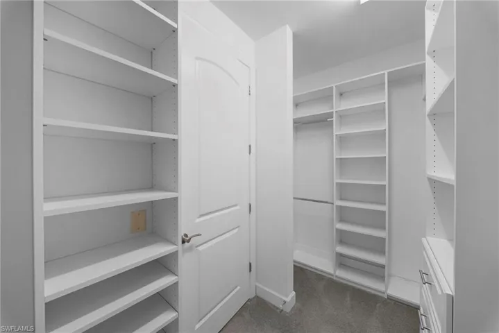 Walk in closet featuring dark colored carpet