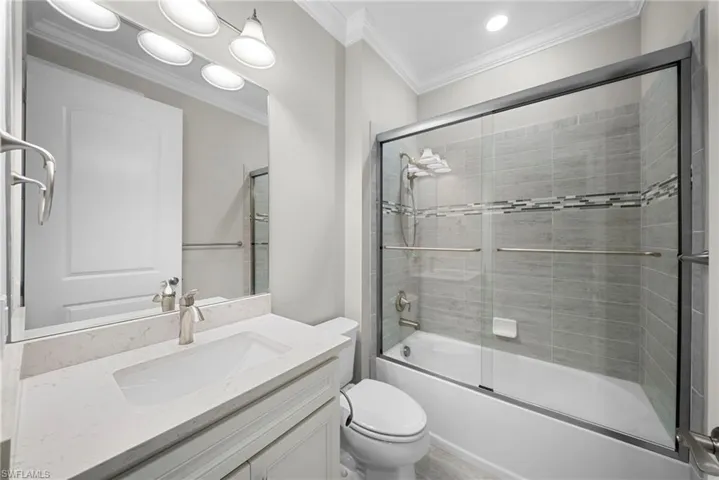 Bathroom with crown molding, vanity, enclosed tub / shower combo, and recessed lighting