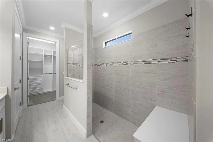 Bathroom with a walk in closet, vanity, a walk in shower, crown molding, and recessed lighting