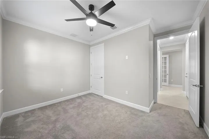 Unfurnished bedroom with crown molding, light colored carpet, and ceiling fan