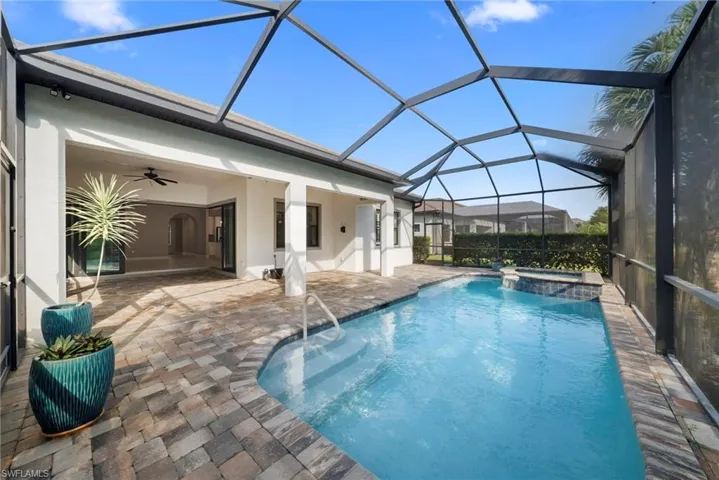 Relaxing pool / spa featuring a sunroom, a patio, and a lanai