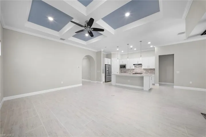 Unfurnished living room with arched walkways, coffered ceiling, a ceiling fan, crown molding, and recessed lighting