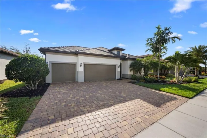 Prairie-style home with decorative driveway, an attached garage, stucco siding, and a front yard