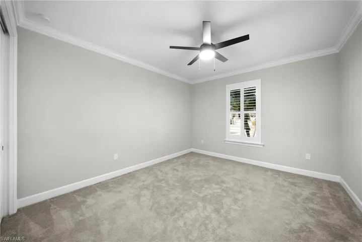 Unfurnished room featuring crown molding, light carpet, and ceiling fan