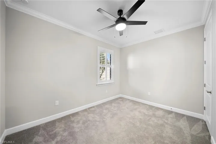 Carpeted spare room featuring crown molding and a ceiling fan