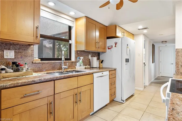 Kitchen with white appliances, a sink, ceiling fan, light tile patterned floors, and tasteful backsplash