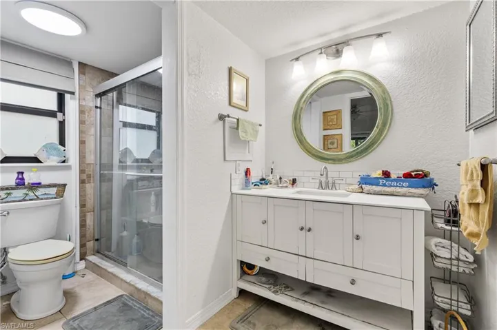 Full bathroom featuring a textured wall, vanity, toilet, a shower stall, and tile patterned flooring