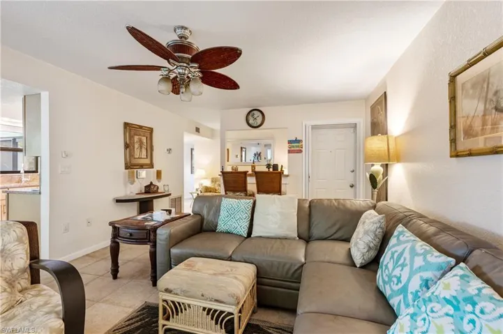 Living room featuring a ceiling fan, light tile patterned floors, and baseboards