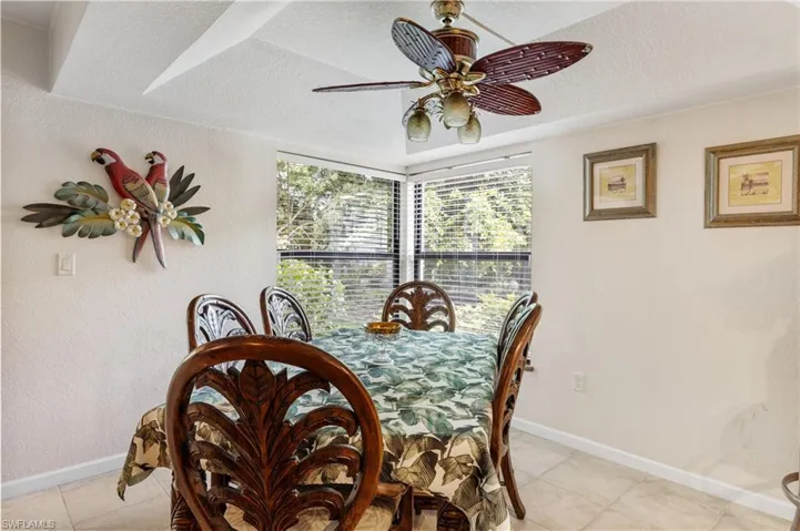 Dining area featuring a textured ceiling, light tile patterned floors, baseboards, and a ceiling fan