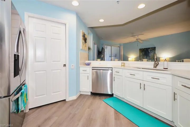 Kitchen with stainless steel appliances, a ceiling fan, light wood finished floors, white cabinetry, and recessed lighting