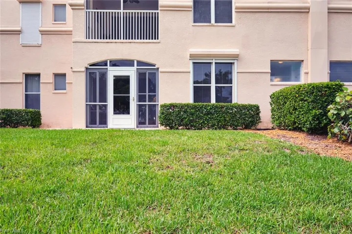 Rear view of property featuring a lawn and stucco siding