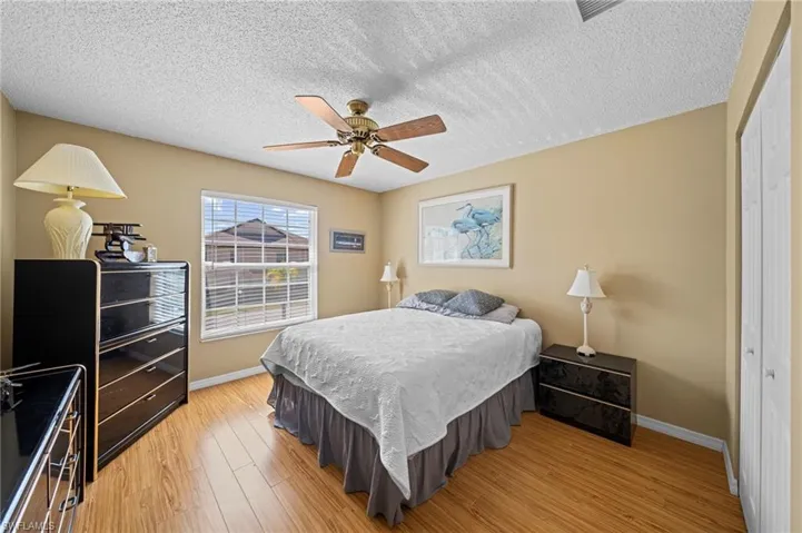 Room featuring wood-finish flooring, a window with horizontal blinds, and a ceiling fan with integrated lighting