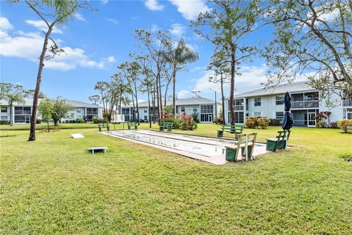 Expansive outdoor recreational area featuring a shuffleboard court and multiple seating benches