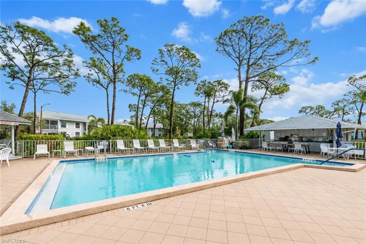 Rectangular swimming pool with a surrounding tiled deck and multiple lounge chairs