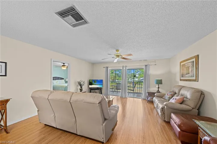 Living area featuring wood-finish flooring, light-toned walls, and a ceiling fan