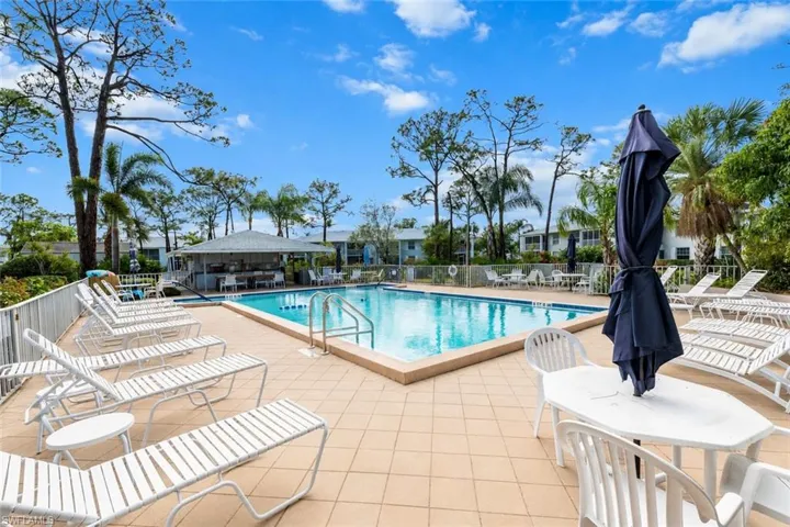 Community swimming pool featuring a perimeter fence and an adjacent covered cabana
