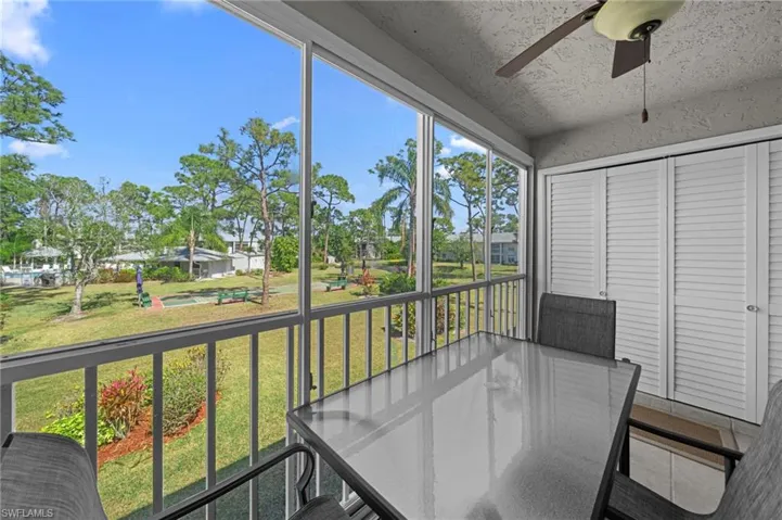 Screened balcony overlooking a landscaped green space with mature trees