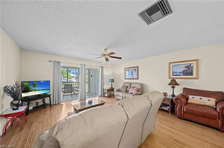 Bright living area featuring wood-finish flooring, light-colored walls, and a ceiling fan