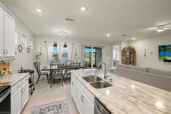 Kitchen with sink, white cabinets, light tile patterned floors, and light stone counters
