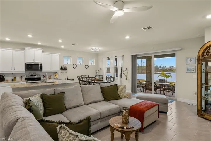 Tiled living room featuring ceiling fan, sink, a water view, and a healthy amount of sunlight