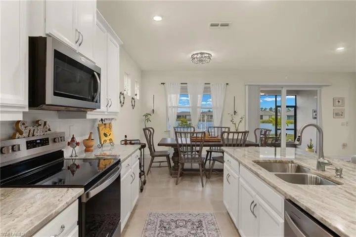 Kitchen featuring sink, light stone counters, white cabinets, and appliances with stainless steel finishes
