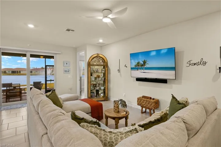 Living room with ceiling fan, light tile patterned floors, and a water view