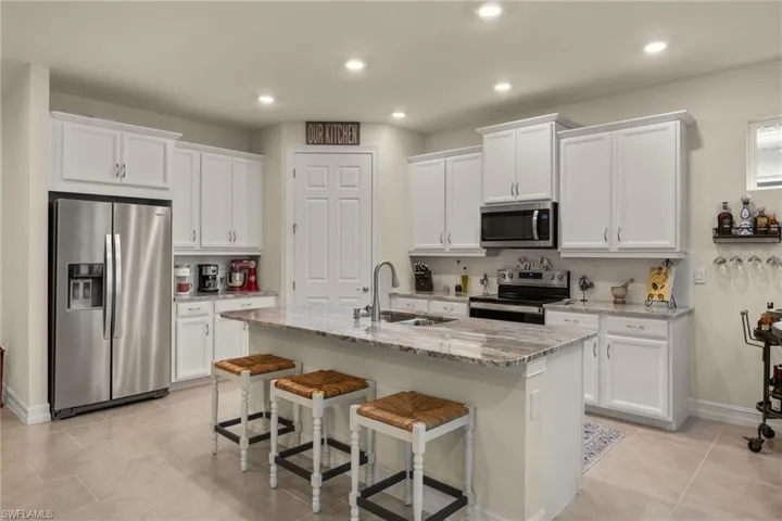 Kitchen with sink, white cabinets, appliances with stainless steel finishes, and an island with sink