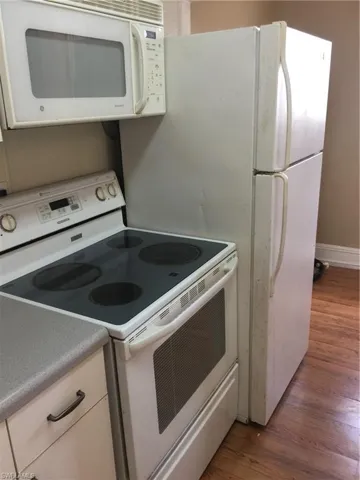 Integrated white microwave, electric range with a smooth cooktop, and a top-freezer refrigerator