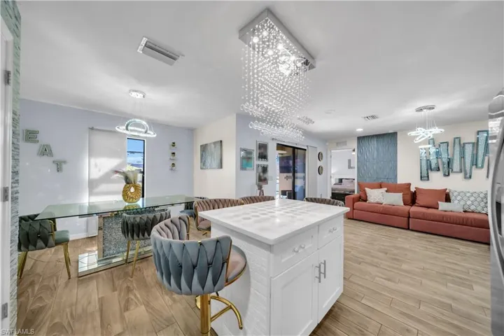 Kitchen featuring a kitchen island, hanging lights, white cabinetry, a breakfast bar area, and open floor plan