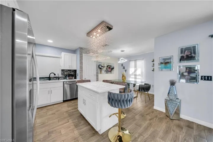 Kitchen featuring stainless steel appliances, wood tiled floors, and white cabinets
