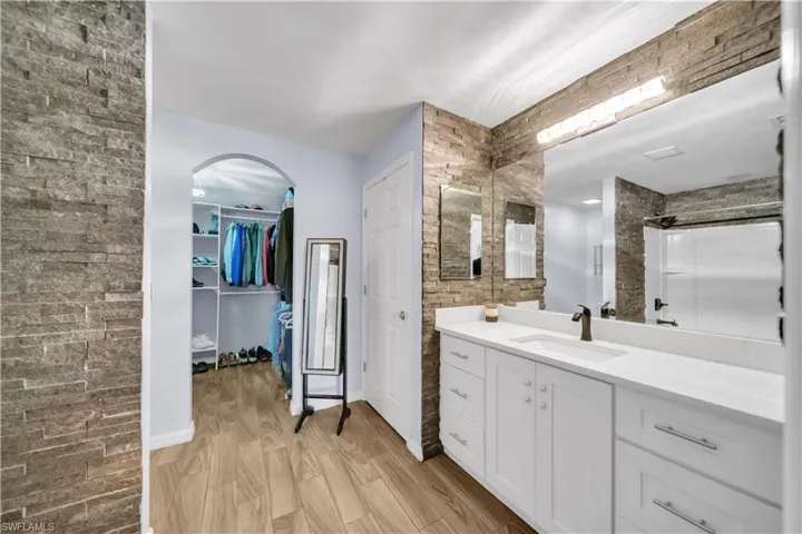 Bathroom with vanity, light wood-type flooring, a walk in closet, and a shower