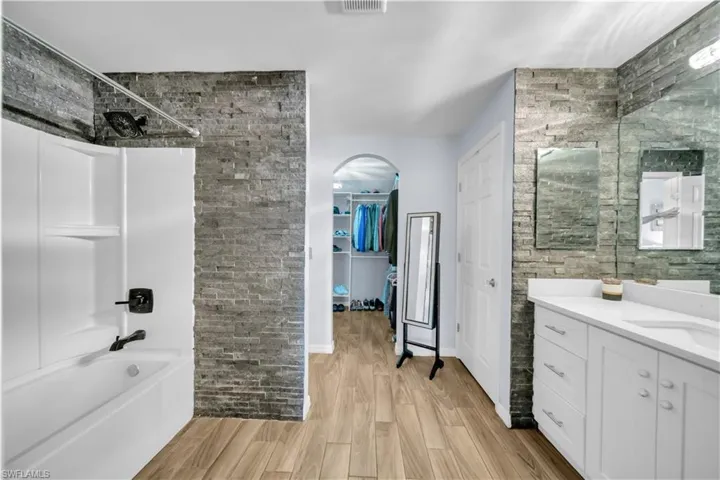 Bathroom featuring vanity, light wood-type flooring, a spacious closet, and shower / bathtub combination