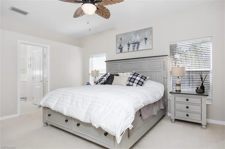 Bedroom with light colored carpet, ceiling fan, and ensuite bath