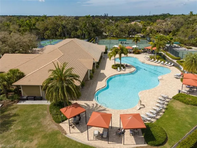 Community pool featuring a patio area, a yard, and view of scattered trees