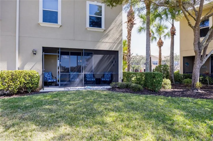 Rear view of house featuring a yard, stucco siding, and a sunroom
