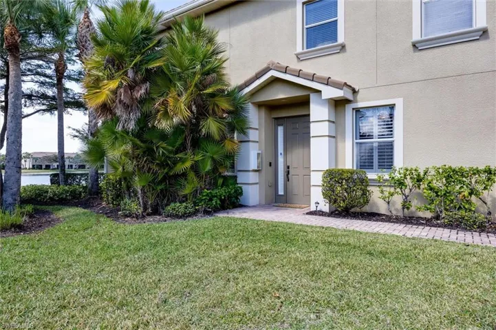 Entrance to property with a lawn and stucco siding