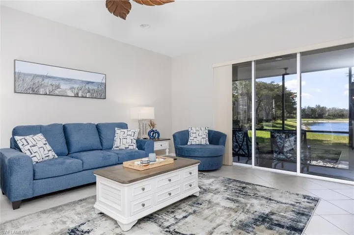 Living room with light tile patterned flooring, a ceiling fan, and a water view