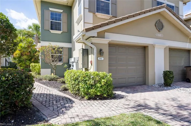 View of front facade with a garage, stucco siding, and decorative driveway
