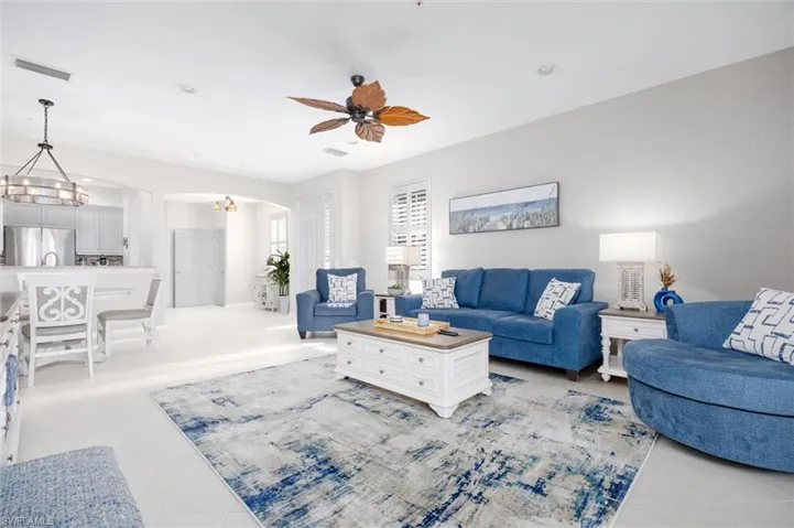 Living area featuring arched walkways, light tile patterned floors, and ceiling fan