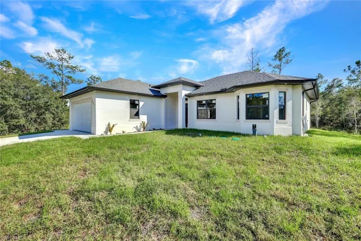 Prairie-style home featuring stucco siding, a front lawn, concrete driveway, and an attached garage