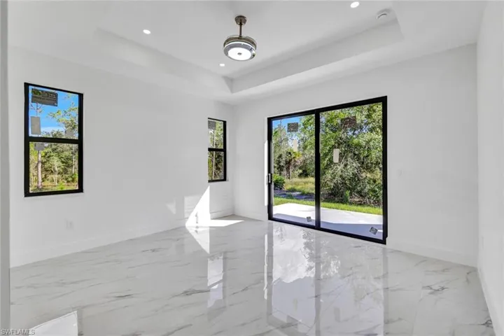 Unfurnished room with light marble finish floors, a tray ceiling, and recessed lighting