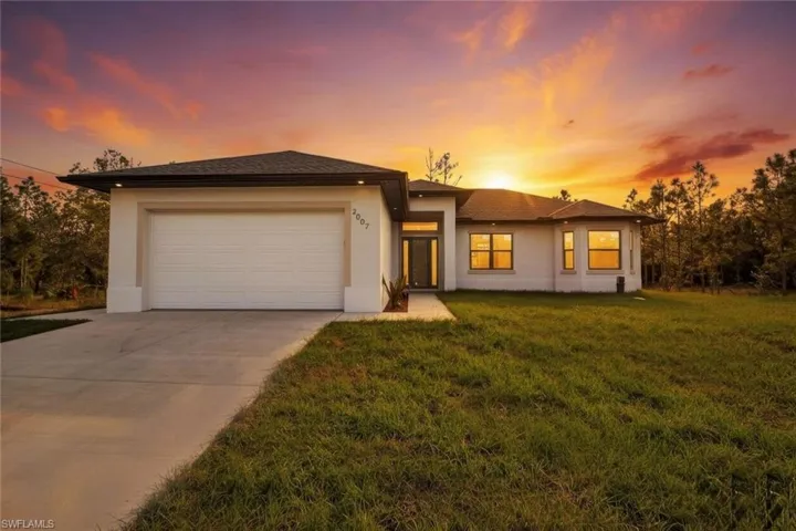 Prairie-style home featuring stucco siding, a front lawn, concrete driveway, and an attached garage