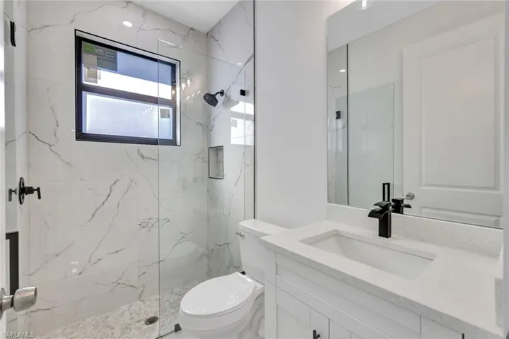 Bathroom featuring vanity and a marble finish shower